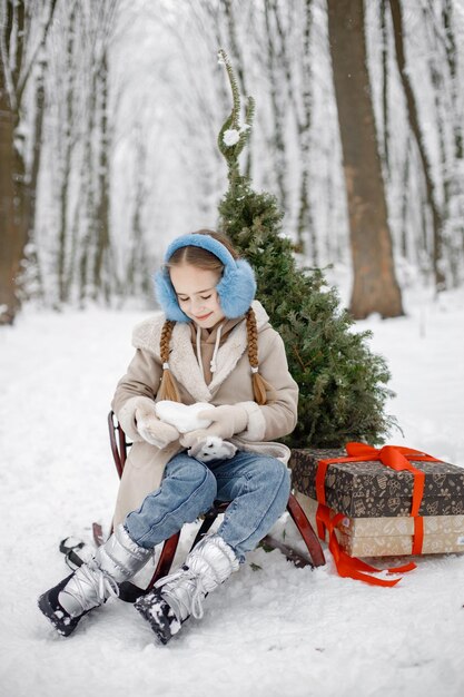 Portrait of a girl sitting in winter forest and posing for a photo