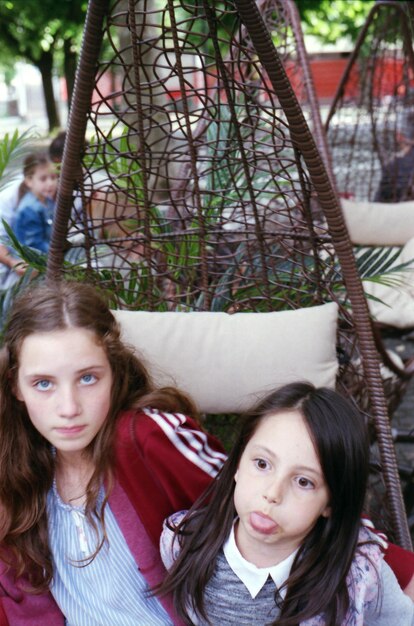 Portrait of girl sitting with sister in swing