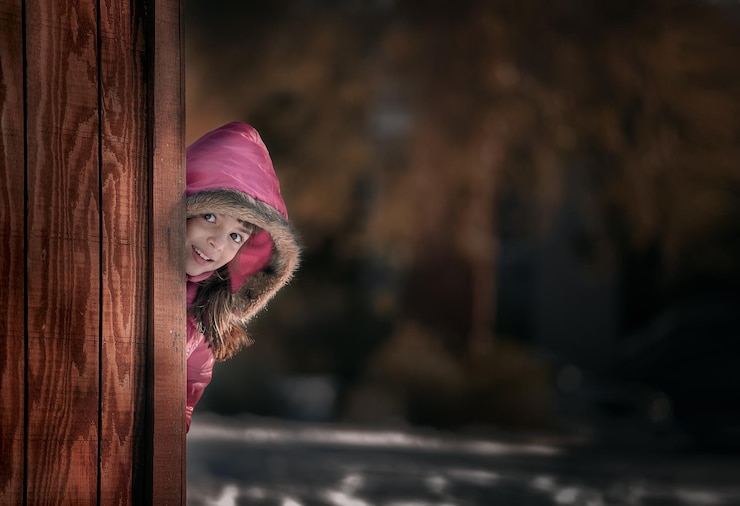 Фотография портрет девушки, улыбающейся, стоящей за деревянной стеной зимой