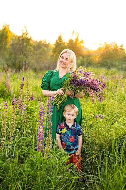 Portrait of a girl and son in a blooming field in the sun at sunset