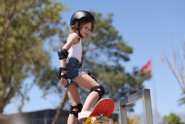 Portrait of girl in special outfit and helmet skating in park skater teen skateboarding extreme