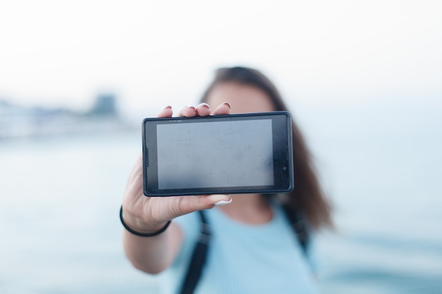 Portrait of girl standing on a beach on holiday taking a selfie