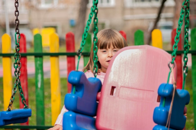 Portrait of girl standing by swing at park