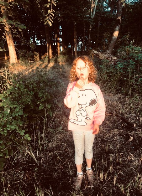 Photo portrait of girl  standing on field in forest