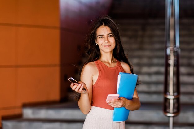 Portrait of a girl student essay in a folder phone and glasses in her hands