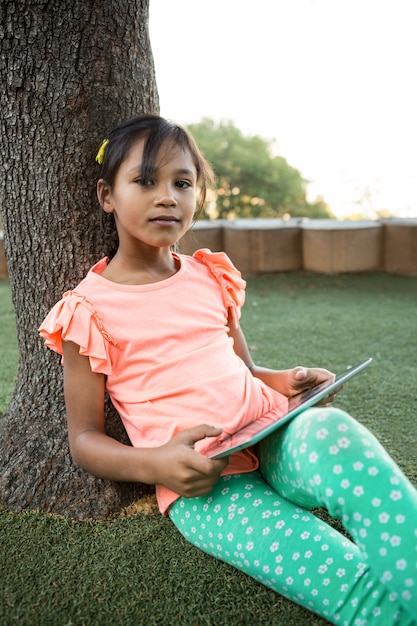 Portrait of girl using digital tablet at park