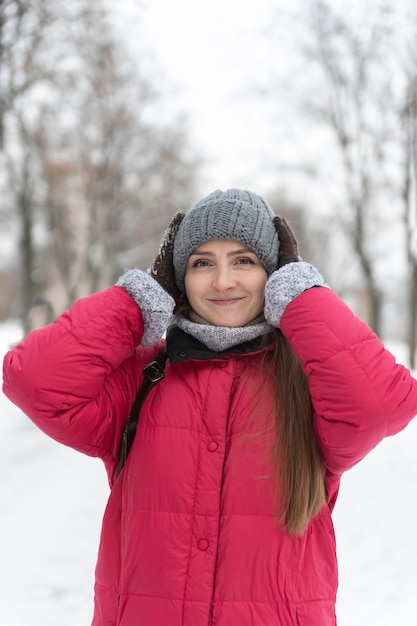 Ritratto di ragazza con cappello caldo sullo sfondo del parco invernale. cornice verticale.