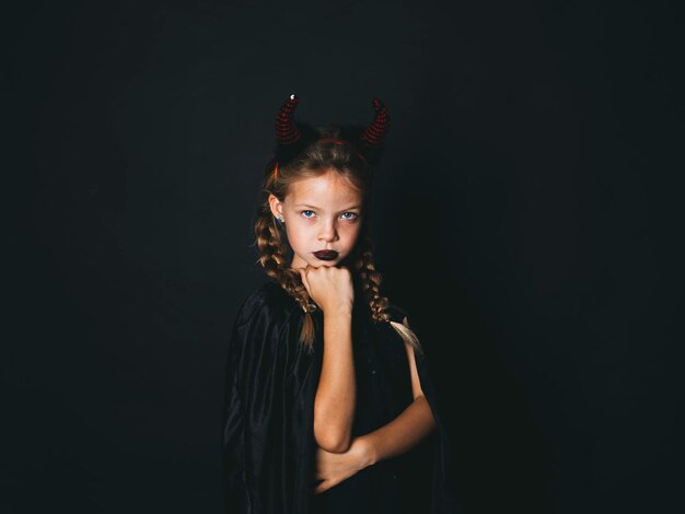 Photo portrait of girl wearing devil costume against black background