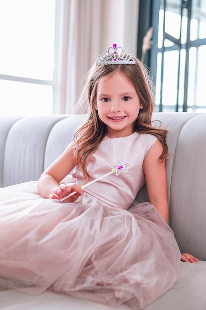 Portrait of girl wearing dress sitting on the couch and smiling looking at the camera