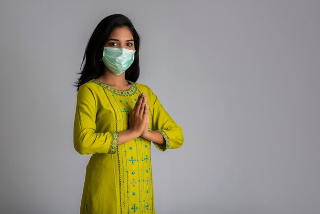 Portrait of a girl wearing a medical mask doing greeting with Namaste gesture.