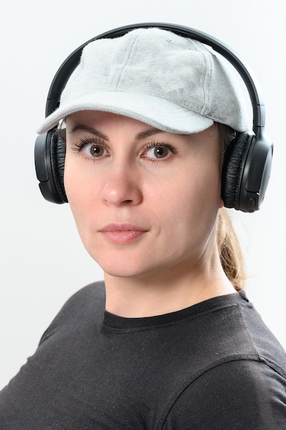 Photo portrait of a girl on a white background with wireless headphones and a hat on her head