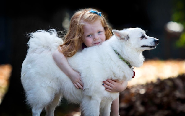 Photo portrait of girl with american eskimo dog in park