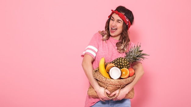 Portrait of a girl with a bag with fruit isolated on a pink wall