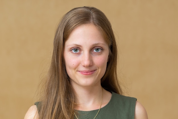 Portrait of girl with blue eyes wearing green dress on brown background