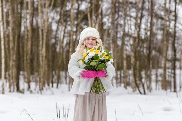 Ritratto di una ragazza con un mazzo di fiori nella foresta in inverno