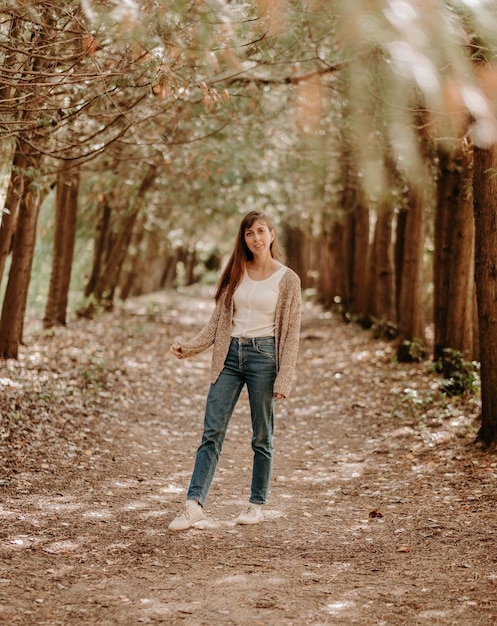 Portrait of a girl with brown hair in a cardigan on a walk in the forest