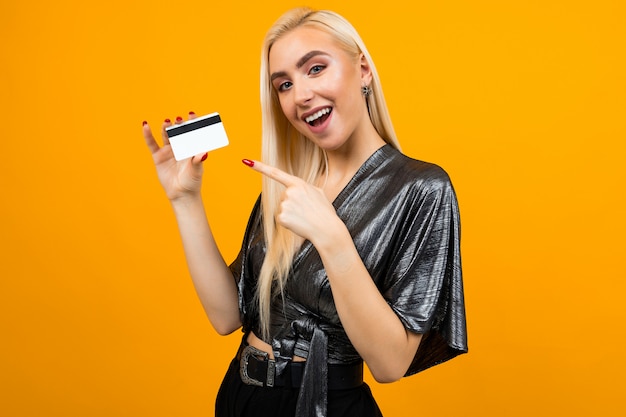 Portrait of a girl with a card with a mockup for shopping on a yellow space