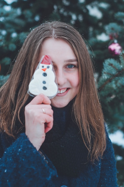 クリスマスプレゼントを持つ少女の肖像画。雪に覆われた冬の夜。