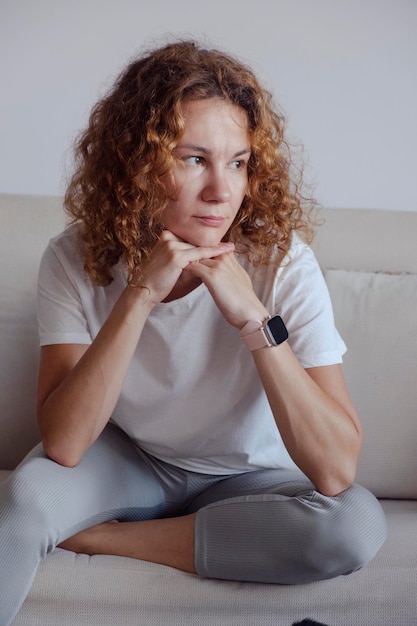 Portrait of a girl with curly hair sitting on sofa High quality photo