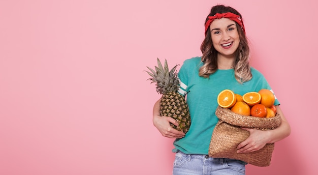 Portrait of a girl with a fruit on a pink wall