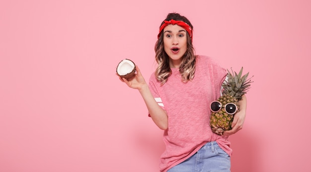 Portrait of a girl with fruit on a pink wall