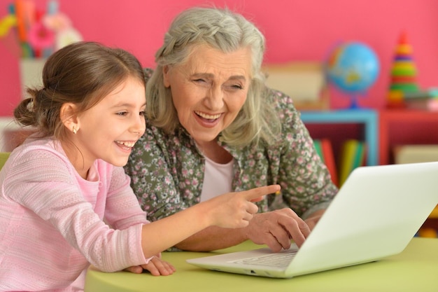 Portrait of girl with grandmother using laptop