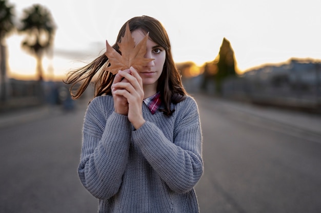 Ritratto di una ragazza con una foglia sul viso in una giornata autunnale.