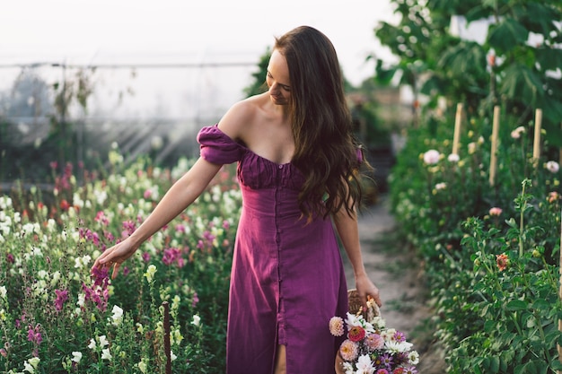 Portrait girl with long hair with a flower basket. Walk in the flower garden. Girl and flowers. Floristics.