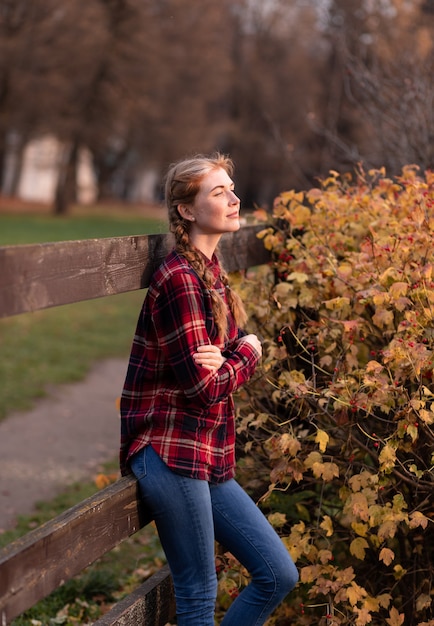 Portrait of a girl with pigtails, standing next to a wooden fence