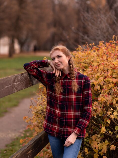 Portrait of a girl with pigtails, standing next to a wooden fence