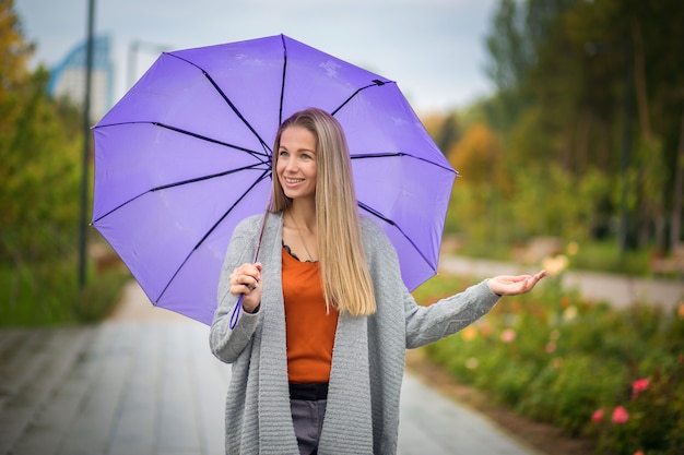 Portrait of a girl with a purple umbrella in an autumn park