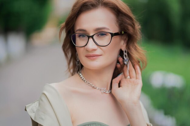 Portrait of a girl with red hair in glasses on the nature