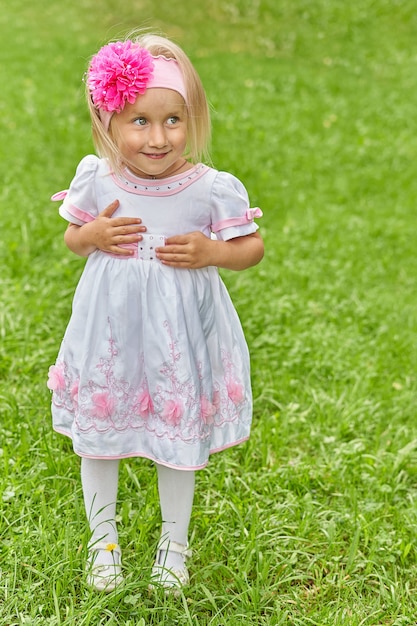 Portrait of a girl with sly eyes in a dress and a bow on her head. The emotion of a child on the street