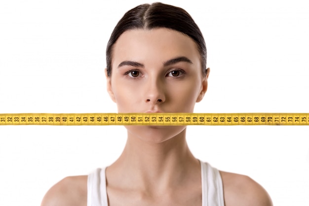 Portrait of girl with a tape measure in front of her mouth. Diet concept