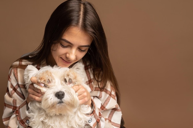 портрет девушки с белой собакой Вест Хайленд Уайт Терьер на коричневом фоне.