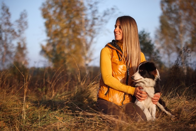 Ritratto di una ragazza in giallo e border collie su uno sfondo di natura.