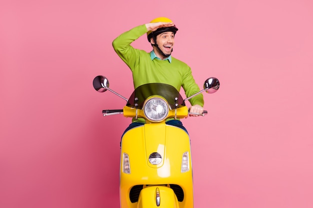 Portrait of glad friendly guy riding moped look side