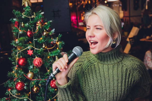 Portrait of a glamorous girl holding a mike and singing.