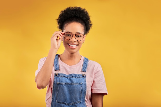 Portrait glasses and smile with a black woman on a yellow background in studio for vision Fashion eyewear and a happy young afro female student at the optometrist for frame lenses or spectacles