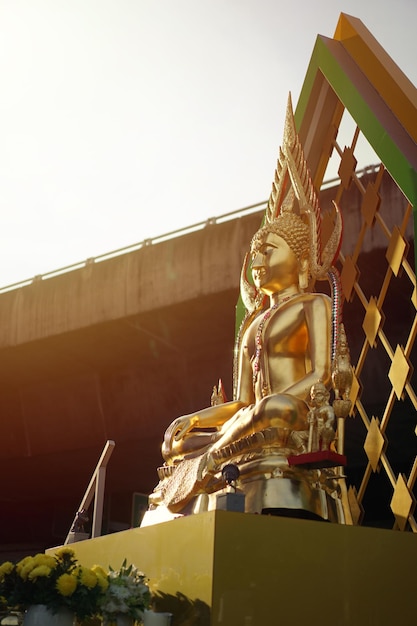 Ritratto statua di buddha in oro con superstrada dietro e effetto luce solare