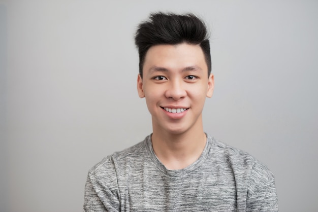 Portrait of good looking asian man over gray background.