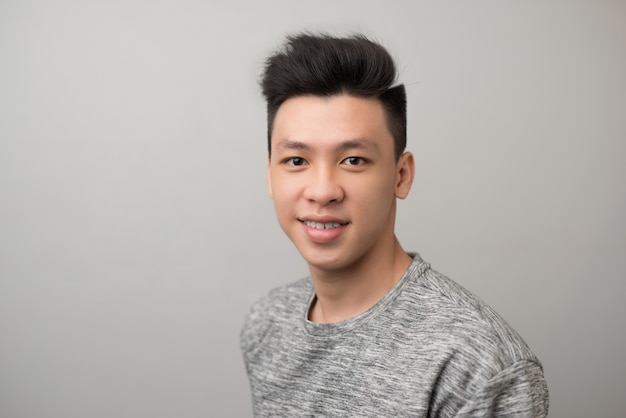 Portrait of good looking asian man over gray background.