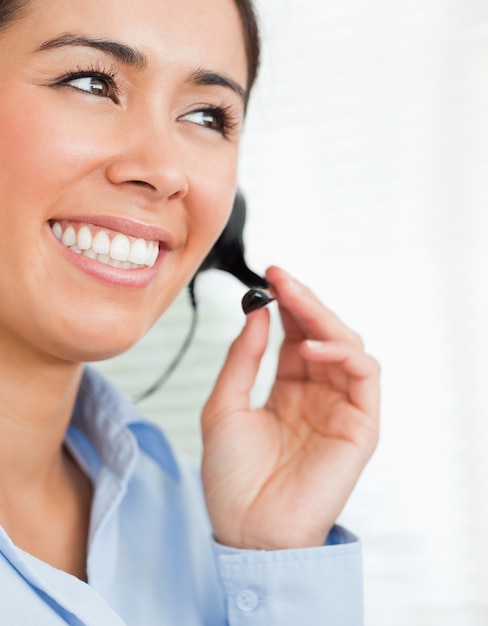 Portrait of a good looking female with a headset helping customers while sitting