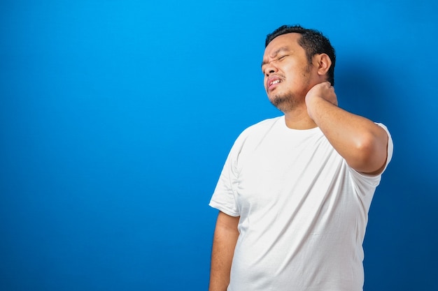 portrait of good looking young asian man in white tshirt having pain on his neck