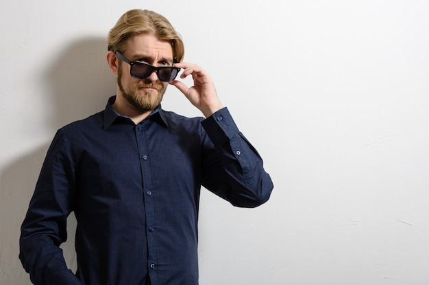 Photo portrait of a good looking young man with sunglasses indoors