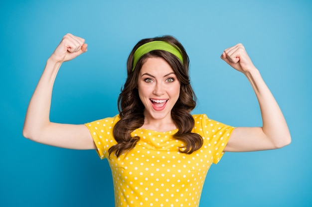 Portrait of good mood energetic girl show her biceps hands isolated over blue color background