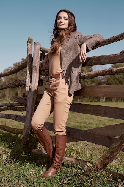Portrait of a gorgeous brunette woman in an elegant checkered brown jacket posing on country landscape