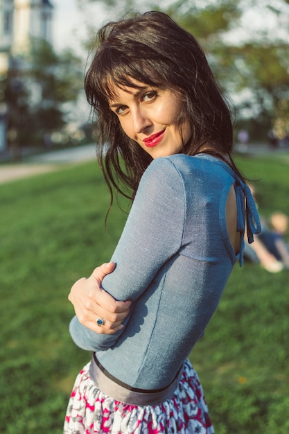 Portrait of an gorgeous girl hugging herself in nature. Stunning woman with luxurious hair