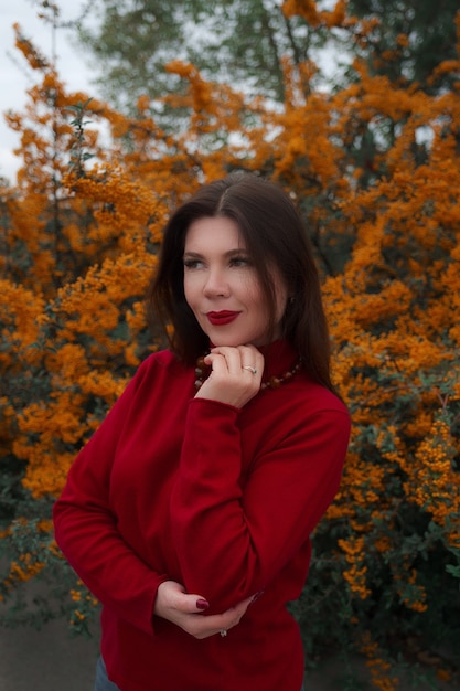 Portrait of a gorgeous middle-aged woman in an autumn park. Hello november. cool red sweater