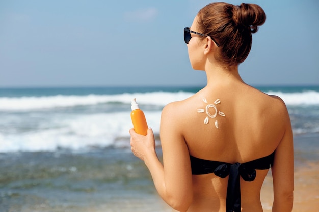 Ritratto di donna splendida in bikini con il sole disegnato su una spalla in spiaggia